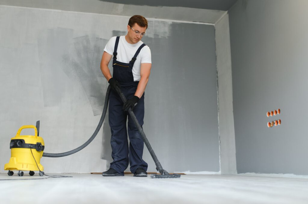 A worker vacuums a room after repairing the floors. Apartment after renovation with a vacuum cleaner